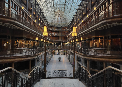 A grand atrium with a glass ceiling, featuring multiple levels, elegant railings, and soft lighting.