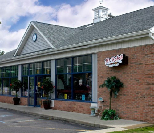 Exterior of Mr. Kabob restaurant featuring large windows, brick facade, and decorative plants.