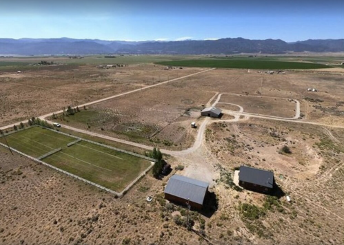 Aerial view of a rural landscape with fields, a few buildings, and a soccer field surrounded by open land.