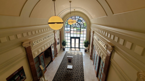 A spacious hallway with large windows, decorative lighting, and signs for the Morrell Museum.