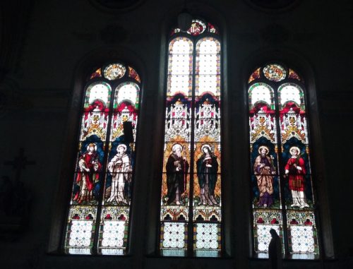 Stained glass windows depicting religious figures in a church, featuring vibrant colors and intricate designs.