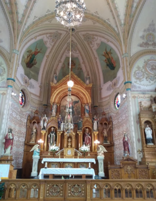 Interior of a church featuring an ornate altar, statues, and decorative murals on the ceiling and walls.