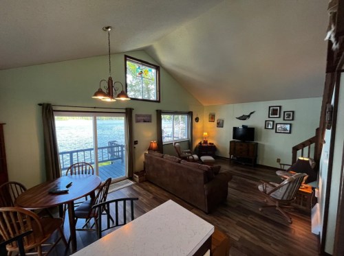 Cozy living area with a view of the water, featuring a sofa, dining table, and large windows.