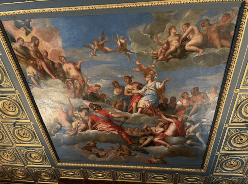Ceiling mural depicting a celestial scene with figures, angels, and clouds in a vibrant, classical style.