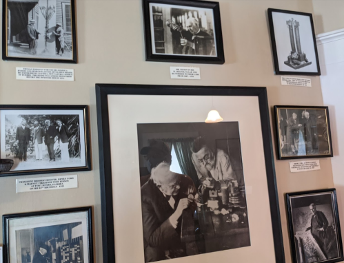 A wall display featuring framed historical photographs and captions, showcasing notable figures and inventions.