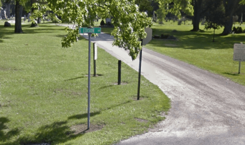 A gravel road curves through a park, with a street sign for Edison Ave visible among green trees.