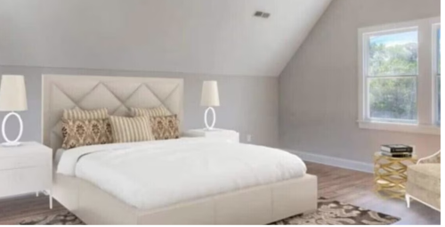 A modern bedroom with a large bed, decorative pillows, two lamps, and a cozy chair by the window.