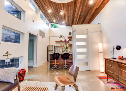 Modern interior featuring a kitchen, dining area, and living space with wooden accents and large windows.