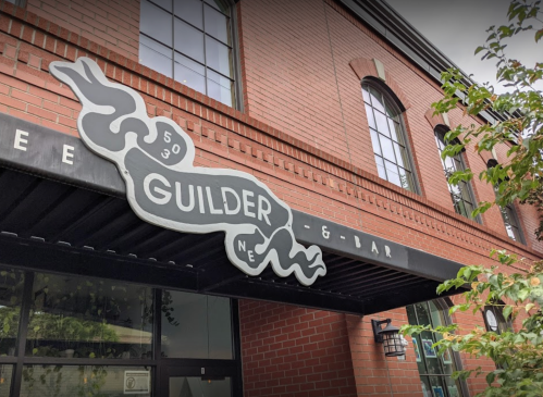 Sign for "Guilder" restaurant and bar on a brick building, featuring a stylized snake design.
