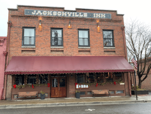 Historic Jacksonville Inn with brick facade, awning, and festive decorations, set in a quaint street scene.