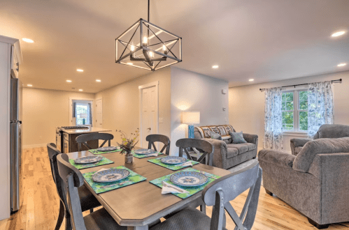 A modern dining area with a table set for four, a cozy living space, and bright lighting throughout.