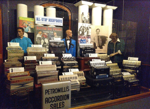 Display of vintage accordions and mannequins in a museum setting, showcasing musical history and memorabilia.