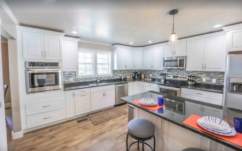 Modern kitchen with white cabinets, stainless steel appliances, a dark countertop, and a cozy dining area.