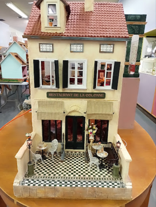 A miniature model of a restaurant with outdoor seating, featuring a tiled patio and decorative details.