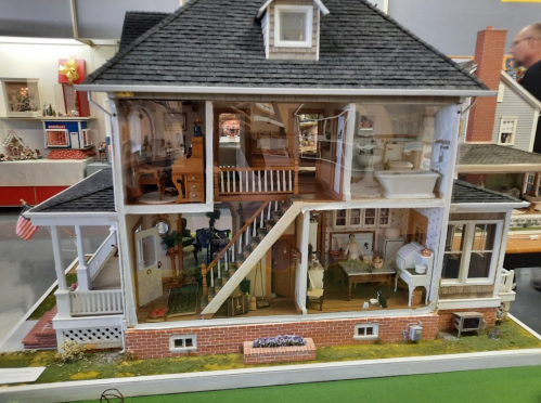 A detailed model of a two-story house, showcasing interior rooms and furniture through a cutaway view.