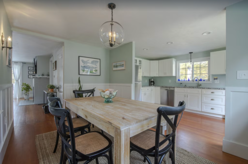 Bright, modern kitchen and dining area with a wooden table, black chairs, and light green walls.
