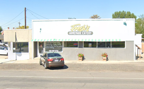 Exterior of Fresh's Homemade Eatery, a one-story building with green and white awning, parked car, and flower pots.