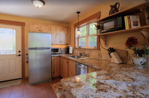 Cozy kitchen with wooden cabinets, granite countertops, stainless steel appliances, and a door leading outside.