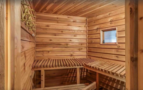 A wooden sauna interior with slatted benches and a small window, featuring warm, natural wood paneling.
