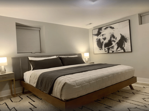 A modern bedroom featuring a large bed, abstract wall art, and two bedside lamps on nightstands.