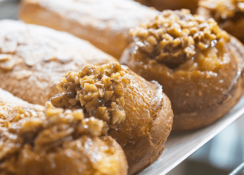 A close-up of sweet pastries topped with chopped nuts, arranged on a tray.