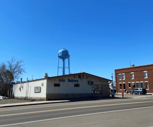 A bakery building with a water tower nearby, set against a clear blue sky and a quiet street.