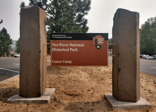 Sign for Nez Perce National Historical Park at Canoe Camp, framed by two large stone pillars.