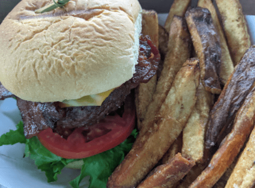 A juicy burger with bacon, cheese, lettuce, and tomato, served with a side of golden, crispy fries.