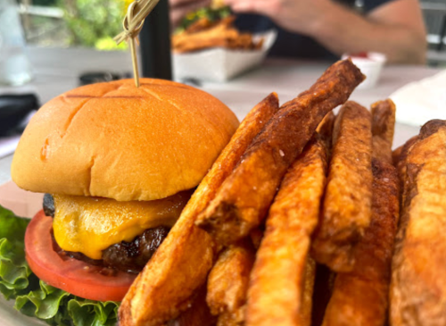 A cheeseburger with lettuce and tomato, served with a side of golden, crispy French fries.