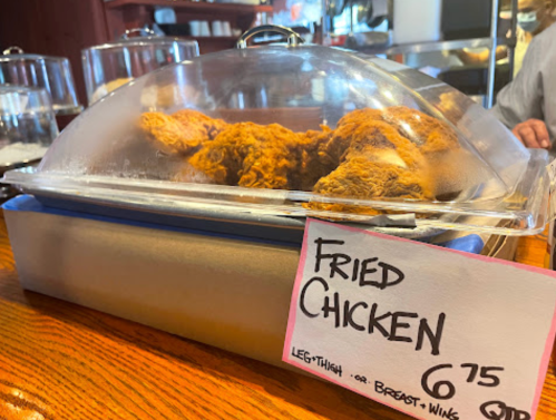 A covered dish of fried chicken with a price tag of $6.75, featuring legs, thighs, and wings.