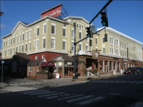 Historic building with a green facade, street signs, and a red traffic light at a crosswalk.