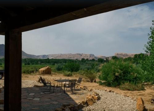 A scenic view of a desert landscape with mountains in the background, featuring a stone patio and outdoor seating.