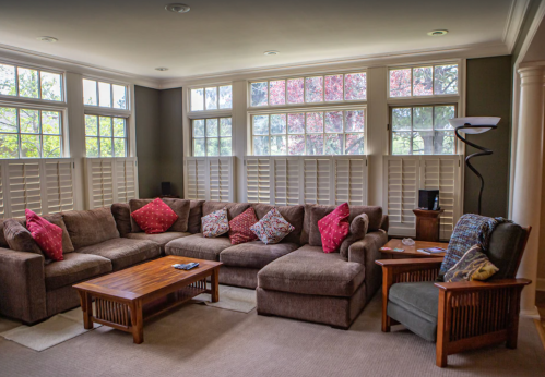 Cozy living room with a large sectional sofa, decorative pillows, wooden coffee table, and bright windows.