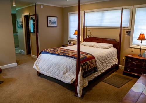 Cozy bedroom featuring a four-poster bed, warm lighting, and a wooden dresser in a softly lit space.