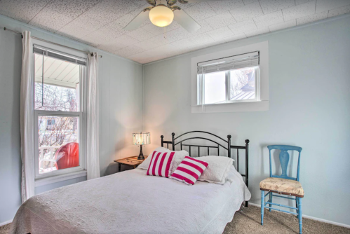 Cozy bedroom with a bed, decorative pillows, a chair, and a window letting in natural light.