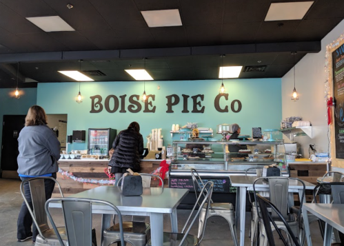 Interior of Boise Pie Co, featuring a counter with pies and customers waiting, with a blue wall and industrial-style seating.