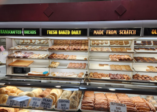 A bakery display case filled with various breads and pastries, labeled with signs for fresh and handcrafted items.