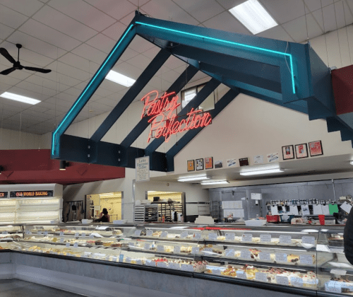 Interior of a bakery featuring a display case of pastries and a neon sign reading "Pastry Perfection."