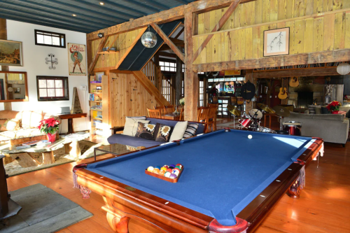 A cozy interior featuring a pool table, wooden beams, and a mix of seating areas in a rustic-style room.