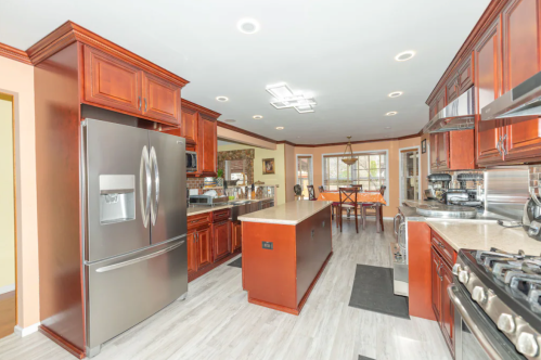 Modern kitchen with dark wood cabinets, stainless steel appliances, and a central island, featuring a bright, open layout.