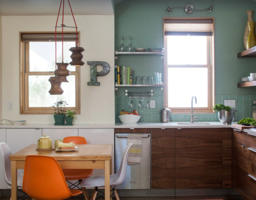 Modern kitchen with green walls, wooden cabinets, a dining table, and stylish decor elements.