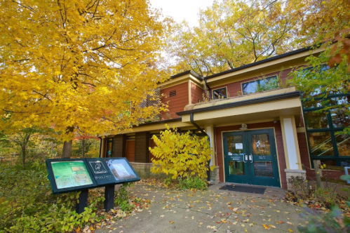 A cozy building surrounded by vibrant autumn foliage and informational signs in front.