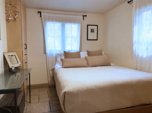 Cozy bedroom with a large bed, neutral decor, and natural light from windows.