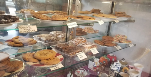A display case filled with various cookies, including chocolate chip, peanut butter, and decorated treats.