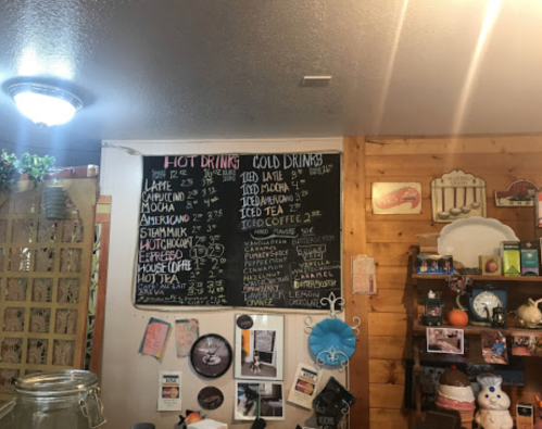 A chalkboard menu displaying hot and cold drink options with prices in a cozy café setting.