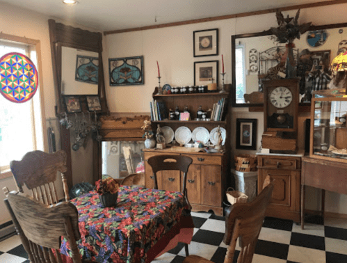 Cozy vintage dining area with a patterned tablecloth, wooden furniture, and decorative mirrors on the walls.