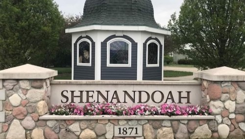 A stone sign reading "Shenandoah 1871" with a gazebo in the background, surrounded by greenery and flowers.