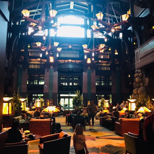 A spacious lodge interior with wooden beams, cozy seating, and warm lighting, filled with guests enjoying the atmosphere.
