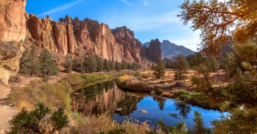 A crooked river winds through tall rock formations on a clear day in Oregon.