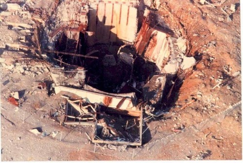 Aerial view of a large, collapsed structure surrounded by debris and rubble, indicating significant damage.
